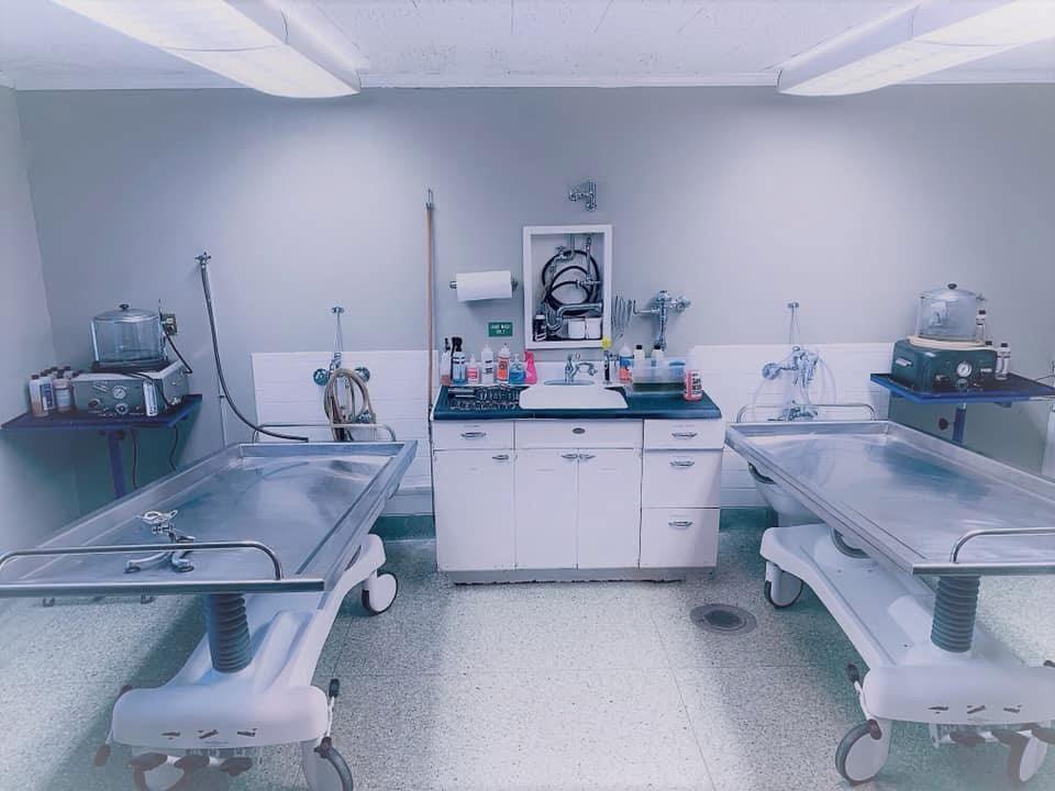 A side-by-side view of a hydraulic embalming table and a folded dressing table, emphasizing space-saving design